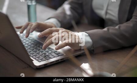 Gros plan sur les mains d'une femme d'affaires tapant sur le clavier d'un ordinateur portable, femme en tenue de travail travaille avec un ordinateur assis au bureau avec assainisseur Banque D'Images