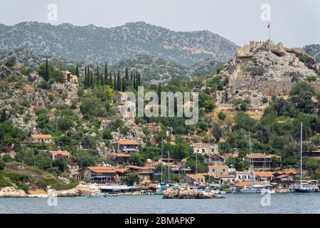 Kalekoy, Simena , Turquie - 03 juin 2019 : village de Kalekoy avec maisons en pierre et château au sommet de la colline dans la baie d'Uchagiz en Turquie, près de la ville en contrebas Banque D'Images