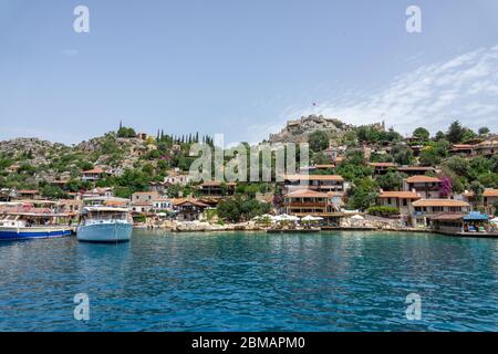 Kalekoy, Simena , Turquie - 03 juin 2019 : village de Kalekoy avec maisons en pierre et château au sommet de la colline dans la baie d'Uchagiz en Turquie, près de la ville en contrebas Banque D'Images