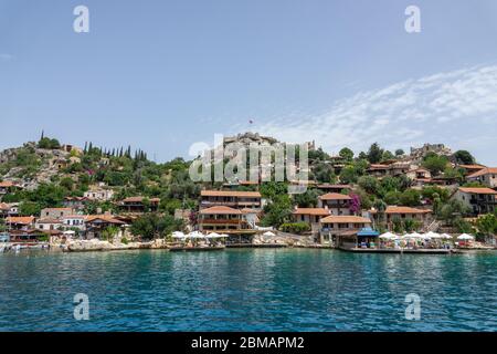 Kalekoy, Simena , Turquie - 03 juin 2019 : village de Kalekoy avec maisons en pierre et château au sommet de la colline dans la baie d'Uchagiz en Turquie, près de la ville en contrebas Banque D'Images