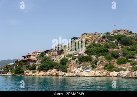 Kalekoy, Simena , Turquie - 03 juin 2019 : village de Kalekoy avec maisons en pierre et château au sommet de la colline dans la baie d'Uchagiz en Turquie, près de la ville en contrebas Banque D'Images