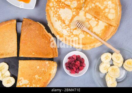 Crêpes avec baies et miel pour le petit déjeuner sur table rustique grise Banque D'Images