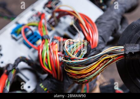 Un ensemble de fils électriques multicolores - bleu, vert, rouge et jaune, enroulé avec du ruban isolant menant aux connecteurs lors de la réparation du réseau par Banque D'Images