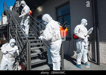 Pandémie de coronavirus. Un désinfectant dans un costume de protection et un masque vaporise des désinfectants à la maison ou au bureau. Protection contre la maladie de COVID-19. Prévention de la propagation du virus de la pneumonie avec des surfaces. Banque D'Images