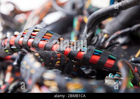 Profilé de câble rouge enroulé avec du ruban isolant noir, en gros plan parmi les fils électriques de différentes couleurs de type et de taille. Le réseau Internet numérique Banque D'Images