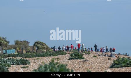 Littlehampton UK 8 mai 2020 - les gens se rassemblent sur la plage de Ferring, près de Worthing, pour observer le spitfire survoler au loin pour commémorer l'anniversaire de la Ve Day, pendant les restrictions de confinement de la pandémie COVID-19 du coronavirus. Il y a 75 ans que la victoire en Europe sur les Allemands a été annoncée pendant la deuxième Guerre mondiale : crédit Simon Dack / Alamy Live News Banque D'Images