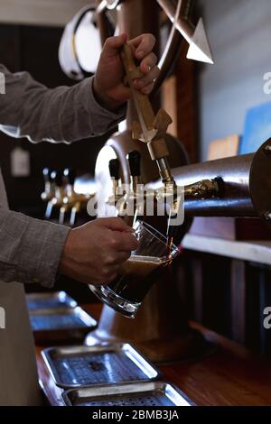 Homme de race blanche servant une pinte de bière dans une brasserie Banque D'Images