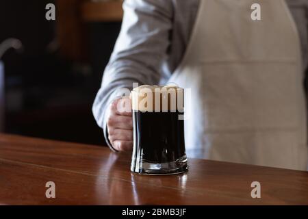 Homme de race blanche servant une pinte de bière dans une brasserie Banque D'Images