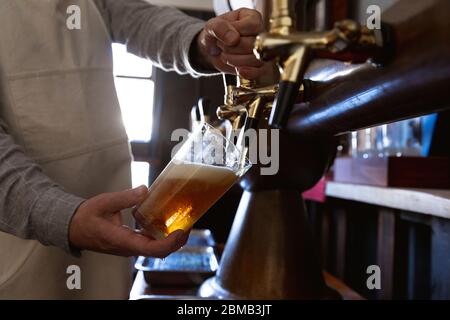 Homme de race blanche servant une pinte de bière dans une brasserie Banque D'Images