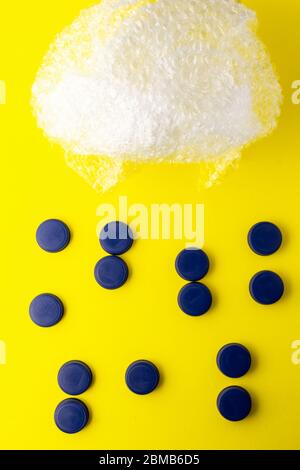 Photo conceptuelle de bulles en plastique représentant un nuage et des bouchons bleus représentant l'eau de pluie sur fond jaune. Recyclage du plastique sur le Banque D'Images
