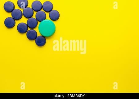 Bouchons de bouteille en plastique situés dans le coin supérieur gauche sur fond jaune. Concept de recyclage dans le conteneur jaune. Banque D'Images