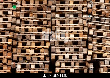 Texture et arrière-plan pour papier peint en poutres et bâtons de bois - palettes empilées en piles et debout près du mur. Plates-formes de stockage et de transport Banque D'Images