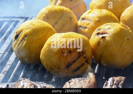Boules de polenta et fromage au milieu de lui, appelé bulz, un plat traditionnel roumain. Rôtir la polenta et le fromage sur un grill extérieur, avec des moutons s Banque D'Images