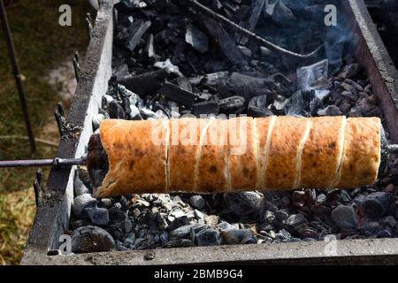 Kurtos kalacs ou des gâteaux de cheminée, la préparation de la cuisine sur le charbon de bois, la rue de cuisine traditionnelle hongroise, pendant le festival de la nourriture. Kurtos Kalacs traditiona Banque D'Images