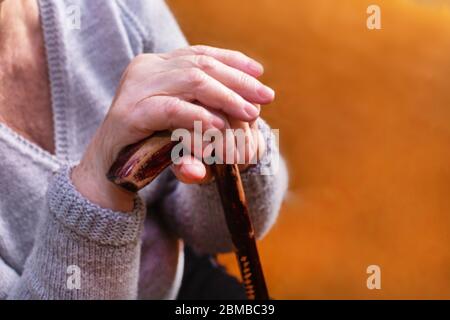 Les mains d'une femme handicapée senior tiennent le bâton de marche. Gros plan Banque D'Images