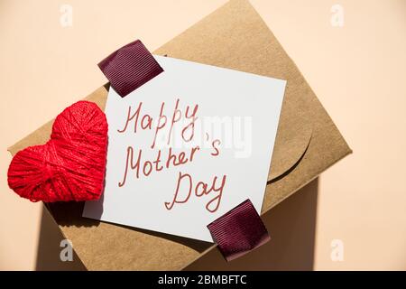 Message de la fête des mères avec cœur fait à la main. Carte de fête des mères.boîte cadeau de vacances sur fond pastel. Banque D'Images