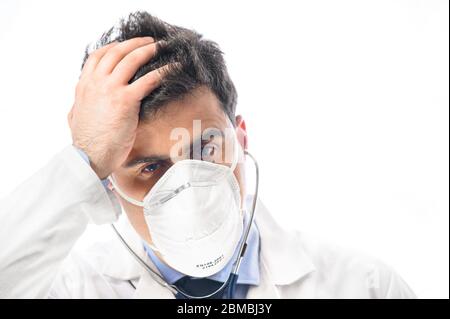 Médecin anxieux et nerveux. Portrait en gros plan d'un médecin en masque protecteur avec expression inquiète, dont les mains ont mis sur la tête. Éclosion pandémique du coronavirus . Banque D'Images