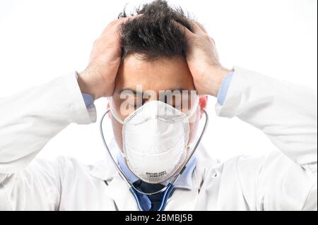 Médecin anxieux et nerveux. Portrait en gros plan d'un médecin en masque protecteur avec expression inquiète, dont les mains ont mis sur la tête. Éclosion pandémique du coronavirus . Banque D'Images