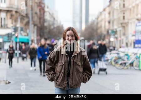 Jeune femme souriant sur City Street avec une foule de gens en arrière-plan Banque D'Images