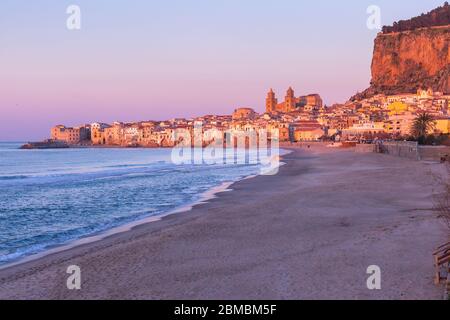 Belle vue sur la plage vide, la cathédrale de Cefalu et la vieille ville de la ville côtière de Cefalu au coucher du soleil rose, Sicile, Italie Banque D'Images