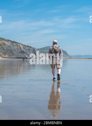 Charmouth Dorset, Royaume-Uni. 8 mai 2020. Météo au Royaume-Uni : un après-midi de vacances chaud et ensoleillé à Charmouth, West Dorset. Malgré le beau temps, les plages restent calmes le 75e anniversaire de la Ve journée, alors que les gens continuent de suivre les conseils pour rester à la maison pendant le confinement pandémique du coronavirus. Un homme marche sur la plage déserte. Crédit : Celia McMahon/Alay Live News Banque D'Images