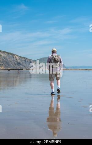 Charmouth Dorset, Royaume-Uni. 8 mai 2020. Météo au Royaume-Uni : un après-midi de vacances chaud et ensoleillé à Charmouth, West Dorset. Malgré le beau temps, les plages restent calmes le 75e anniversaire de la Ve journée, alors que les gens continuent de suivre les conseils pour rester à la maison pendant le confinement pandémique du coronavirus. Un homme marche sur la plage déserte. Crédit : Celia McMahon/Alay Live News Banque D'Images