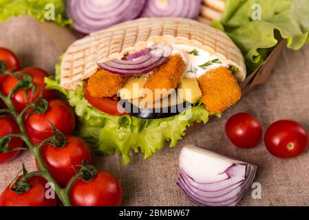 Pita Doner kebab avec salade verte, tomates cerises, sans pomme de terre, bâtonnets de poisson grillés. Cuisine de rue. Restauration rapide. Un kebab Banque D'Images