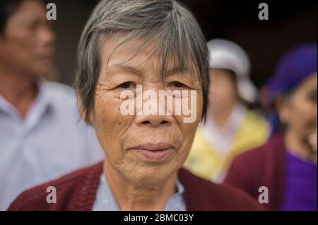 Dalat, Lâm Đồng, Vietnam - 21 février 2011 : femme vietnamienne senior aux cheveux gris attendant à l'arrêt de bus, sourit Banque D'Images