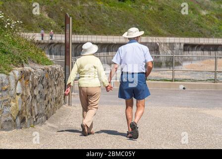 Lyme Regis Dorset, Royaume-Uni. 8 mai 2020. Météo au Royaume-Uni: Un chaud et ensoleillé après-midi de vacances en banque à Lyme Regis, West Dorset. Une promenade en couple le long du front de mer vers Charmouth. Crédit : Celia McMahon/Alay Live News. Banque D'Images