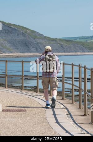 Lyme Regis Dorset, Royaume-Uni. 8 mai 2020. Météo au Royaume-Uni: Un chaud et ensoleillé après-midi de vacances en banque à Lyme Regis, West Dorset. Un homme marche le long du front de mer vers Charmouth. Crédit : Celia McMahon/Alay Live News Banque D'Images