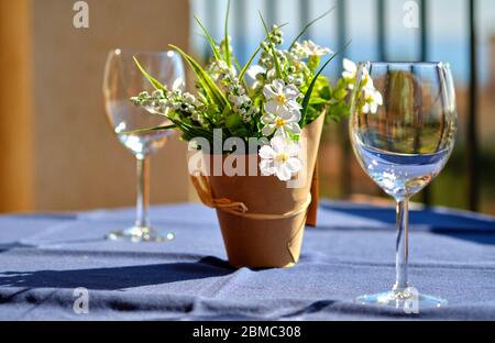 Deux verres à vin en cristal propre et une jolie plante artificielle en pot à fleurs sur la table en terrasse d'été par temps chaud Banque D'Images