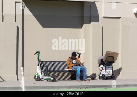 Un homme sans abri nap dans la rue dans le quartier Soma de San Francisco, Californie. Livre de Frye Gaillard UNE PLUIE DURE est vue sur le banc. Banque D'Images