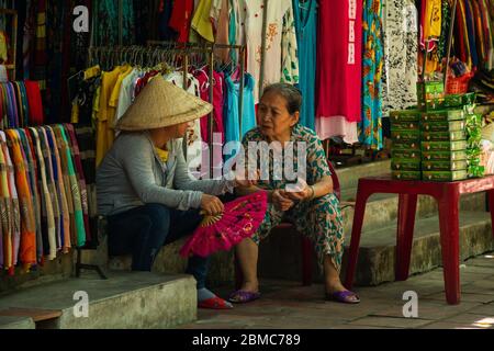 Deux femmes qui parlent devant un tailleur à Hoi an, au Vietnam Banque D'Images