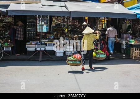 Femme portant des paniers de légumes avec mât de bambou Banque D'Images