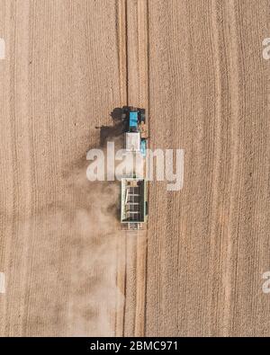 Vue aérienne d'un tracteur bleu travaillant dans un champ avec un épandeur d'engrais et de semences Banque D'Images