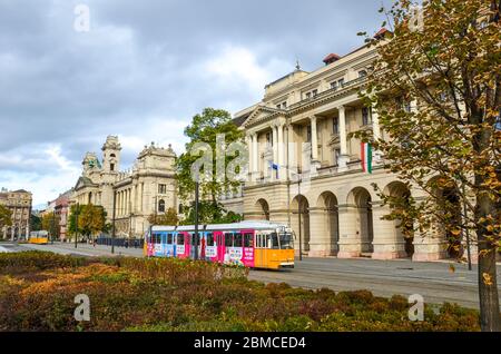 Budapest, Hongrie - 6 novembre 2019 : tramway jaune avec une publicité colorée devant le bâtiment du ministère de l'Agriculture. Musée d'Ethnographie en arrière-plan. Place Kossuth dans le centre-ville. Banque D'Images