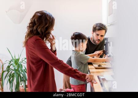 La famille prépare et mange des biscuits au chocolat aux arachides à la maison Banque D'Images