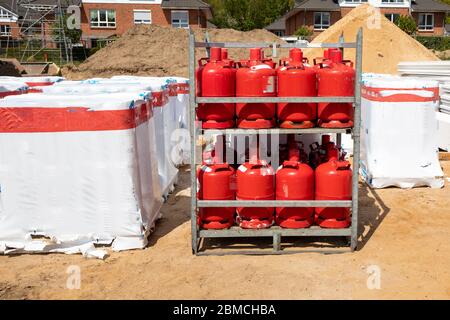 une palette avec bouteilles de gaz rouges est debout sur un chantier de construction Banque D'Images