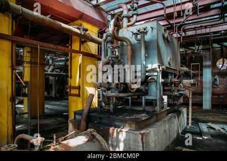 Anciens réservoirs industriels rouillés reliés par des tuyaux reliés à des vannes dans une usine de produits chimiques abandonnée Banque D'Images