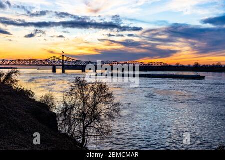 Paysage de coucher de soleil du pont du fleuve Mississippi entre le Mississippi et la Louisiane, à Vicksburg, MS, avec des barges de poussée de remorqueur. Banque D'Images