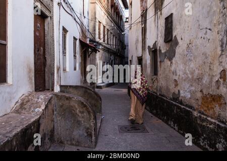 Femme marchant dans la rue à Stone Town, Zanzibar Banque D'Images