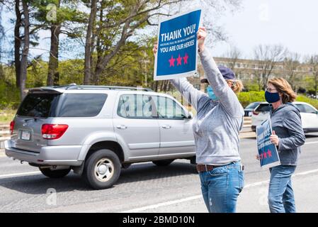 Deux femmes sur le côté de la route, tenant des panneaux et se brandisant sur les voitures sur l'autoroute, félicitant les médecins et les infirmières de l'hôpital Banque D'Images