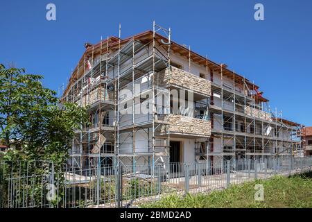 Échafaudage près d'une maison en construction pour les travaux de plâtre externe. Immeuble d'appartements moderne en ville avec balcons en pierre. Banque D'Images