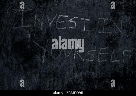 « Invest in self » écrit sur le mur rugueux, plan horizontal. Banque D'Images