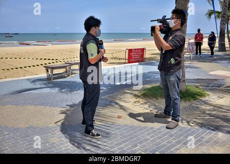 Masque COVID-19. L'équipe de caméras de télévision filme un entretien de diffusion et porte et parle à travers un masque facial coronavirus. Plage de Pattaya, Thaïlande Banque D'Images