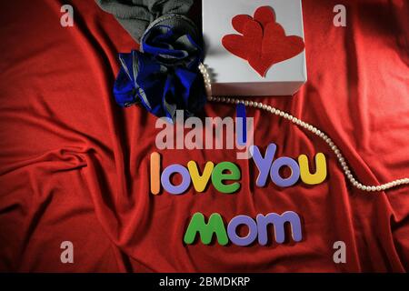 Lettres colorées avec je t'aime maman isolé sur fond rouge tissu. Je t'aime maman orthographié avec des lettres colorées et coeur rouge pour la fête des mères. Banque D'Images