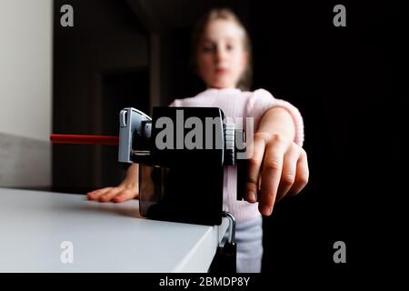 Gros plan grand angle de la main de fille aiguisant crayon rouge avec peu de mise au point Banque D'Images