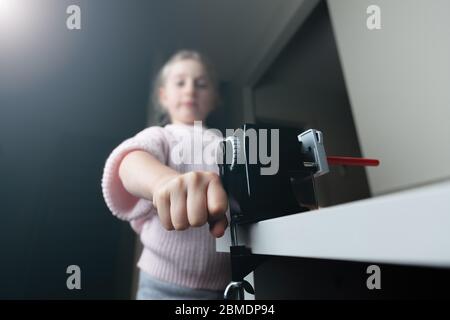 Fille aiguisant un crayon rouge à la maison avec peu de foyer Banque D'Images