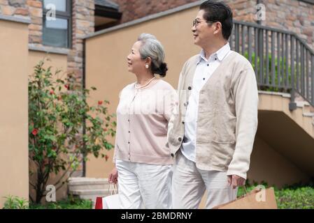 Un couple asiatique âgé tenant des sacs de shopping dans la communauté Banque D'Images