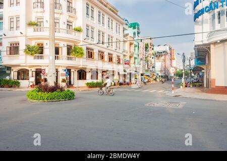 CAN Tho Vietnam - octobre 16 2013; rue de la ville avec bâtiment de style colonial au coin et les gens ont burré en mouvement tôt le matin. Banque D'Images